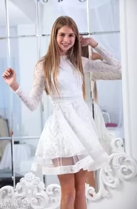 Девушка с брекетами снимает белое кружевное платье на фотосессии